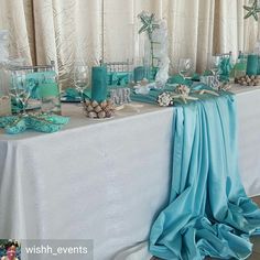 the table is set up with blue and white decorations, candles, and other items