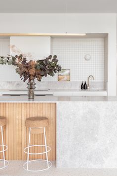 two bar stools sit in front of an island with marble countertops and white walls