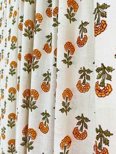 the curtain is lined up with orange and green flowers on white fabric, along with other patterns