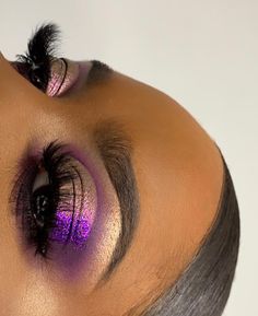 a woman with purple eyeshadow and eyeliner is looking up at the camera