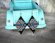 a pair of black, red, and blue beaded earrings sitting on top of a wooden table