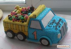 a birthday cake shaped like a dump truck with candy on the side and an iced donut next to it