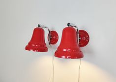 two red telephones are plugged in to the wall with one light on it