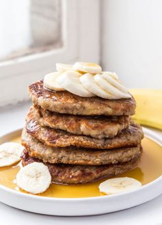 a stack of pancakes with banana slices and syrup