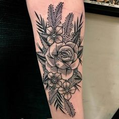 a black and white flower tattoo on the right arm with pine cones, leaves and flowers around it