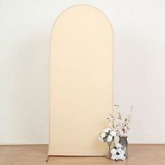 a vase filled with white flowers sitting next to an arch shaped sign on a wooden floor