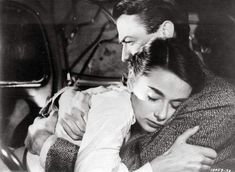 an old black and white photo of a man hugging a woman in the back of a car