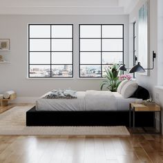 a bed sitting in the middle of a bedroom next to two large windows and a wooden floor