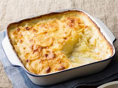 a casserole dish with potatoes in it on a blue and white cloth next to a plate