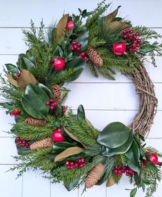 a christmas wreath with pine cones, holly and pomegranates