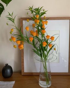 there is a vase with flowers in it on the table next to a framed photograph