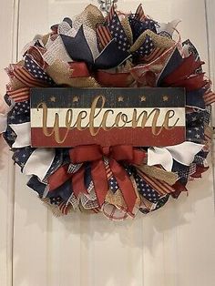 a welcome wreath hanging on the front door with an american flag design and red white and blue ribbons