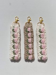 three crocheted key fobs with gold clasps on each side and pink flowers