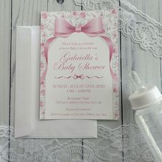 a pink and white baby shower is next to a pacifier on a lace tablecloth