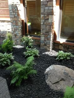 a stone house with plants and rocks in the front yard