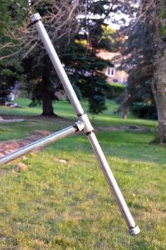 an upside down metal pole in the middle of a grassy area with trees behind it