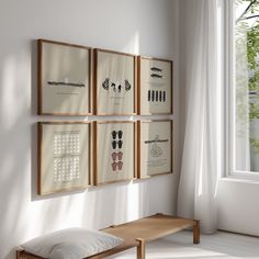 four framed pictures hang on the wall next to a bench in front of a window