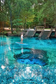 a person standing on a surfboard in the middle of blue water with steps leading up to them