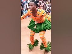 a woman in an orange and green outfit is dancing with grass skirts on her feet