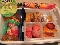 an open lunch box with donuts, fruit and jelly