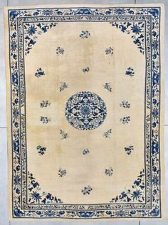 an old rug with blue and white designs on it, sitting on a tile floor