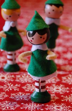 three little elf figurines sitting on top of a red and white table cloth