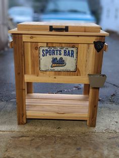 a wooden box sitting on top of a sidewalk next to a parking lot with cars parked in the background