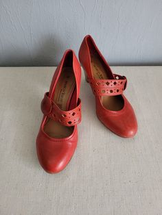 Vintage women`s classic red / apple red leather surface pumps with frontal decorative perforated strap (can`t open). Decorative buttons on the sides. Amazing, comfortable Mary jane style shoes with round toe and chunky, wooden pattern cone heels. EU size 38. GERMANY footwear. Rubber sole.  condition: great, a little bit used vintage. Without serious damages. Some slight scratches on the heels back. measurements: outsole length 27 cm / 10.5" in heels height 6,4 cm / 2.5" in bottom sole width in w Leather Mary Janes With 4-inch Heel And Round Toe, Red Mary Jane Heels With Ankle Strap, Mary Janes With 4-inch Heel And Round Toe, Mary Jane Heels With Red Sole And Round Toe, Red Low Heel Mary Janes For Formal Events, Mary Jane Heels With Red Sole And Ankle Strap, Mary Jane Heels With Red Sole And Closed Toe, Red Closed Toe Mary Janes With Buckle Closure, Red Round Toe Heels With Buckle Closure