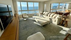 a living room filled with lots of furniture and large windows overlooking the ocean in front of it