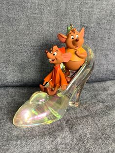 two figurines sitting on top of a glass shoe