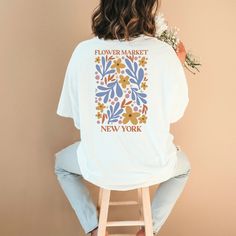 This stunning ladies oversized t-shirt, a perfect blend of style and comfort. This unique piece features a Matisse-inspired Flower market print creating a look that is both artistic and chic. Made from high-quality, soft fabric, this t-shirt offers a relaxed fit that is perfect for everyday wear or dressing up for a special occasion. Made using 100% US cotton that is ethically grown and harvested. Gildan is also a proud member of the US Cotton Trust Protocol ensuring ethical and sustainable means of production. This tee is certified by Oeko-Tex for safety and quality assurance. For an oversized look we recommend going at least 2-3 sizes up! Affordable Fun White Print T-shirt, Oversized Floral Print T-shirt For Spring, Trendy Oversized Floral Print Tops, Oversized Cotton Floral Print Shirt, Oversized White Floral Print Shirt, Oversized White Floral Print T-shirt, Trendy Floral Print Relaxed Fit T-shirt, Spring Oversized Floral Print T-shirt, Oversized Floral Print Crew Neck Top