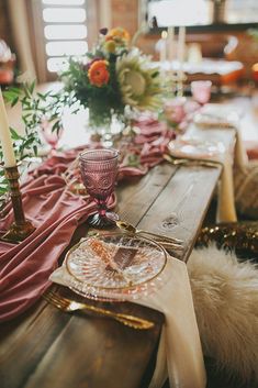 the table is set with pink and gold plates, silverware, and red napkins