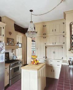 a kitchen with white cabinets and a chandelier hanging from the ceiling