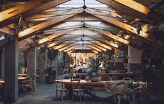 the inside of a building with tables and chairs, potted plants and other items