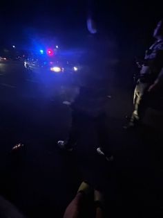 two police officers standing on the side of a road at night with their lights on