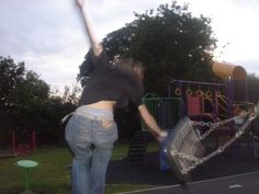 a woman jumping up in the air to catch a frisbee at a playground