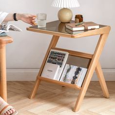 a person sitting at a table with a book and magazine on it, next to a lamp