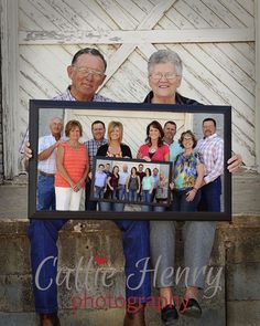 an older couple holding up a framed photo