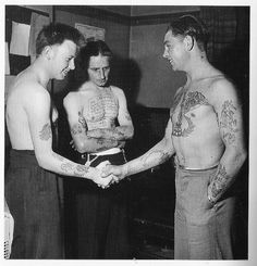 three men with tattoos on their arms and chest are shaking hands in an old photo