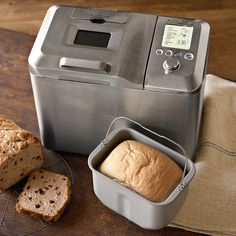 a loaf of bread sitting on top of a cutting board next to an automatic bread maker