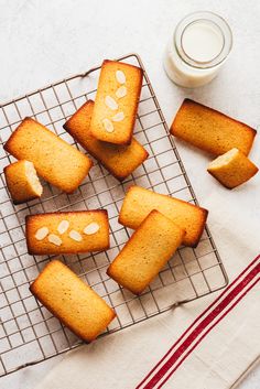 several pieces of bread on a cooling rack next to a cup of milk and napkin