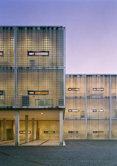 an empty parking lot in front of a tall building with multiple windows and balconies