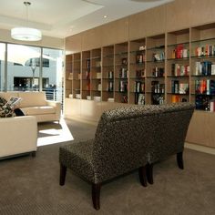 a living room filled with furniture and bookshelves next to a large glass window