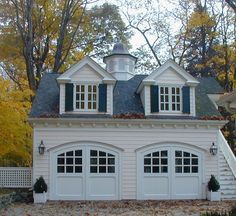 a white two story house with black shutters on the front and side windows, surrounded by fall foliage