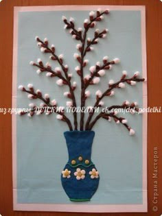 a blue vase filled with white flowers on top of a wooden table next to a wall