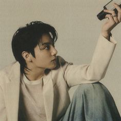 a young man sitting on the ground holding a cell phone up to his ear with one hand