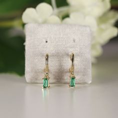 "A pair of green emerald hoop dangle earrings. 14k solid gold. SOLD AS PAIR. Material; 14k solid gold hoops Baguette lab grown emeralds are 4x2mm Prong settings. 14k gold backings included. Emerald is the birthstone for May. As the stone of the heart, Emerald symbolize compassion, and universal love. It is very meaningful choice as Engagement ring. Emerald carries the rich green color of Spring and radiates a beautiful vivid tone. They are considered to be a symbol of rebirth and love. Emerald o Fine Jewelry 14k Gold Baguette Earrings, 14k Gold Baguette Earrings Fine Jewelry, Fine Jewelry Baguette-cut Huggie Earrings As Gift, Elegant Emerald Huggie Earrings As Gift, Dangle Earrings With Baguette Diamonds For Gift, 14k Gold Baguette-cut Huggie Earrings For Gift, Baguette Cut Emerald Earrings As A Gift, Baguette Shaped Jewelry With Prong Setting As A Gift, Luxury Baguette Cut Hoop Earrings As Gift