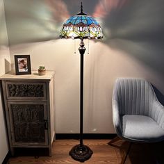 a lamp that is sitting on top of a table next to a chair and cabinet