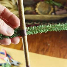 a hand holding a wooden stick with an arrow on it next to a christmas tree