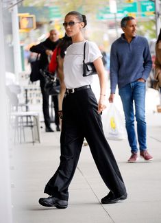 a woman walking down the street wearing black pants